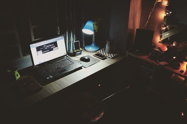 Office Setup Cozy office with laptop, desk lamp, and personal decor at night.