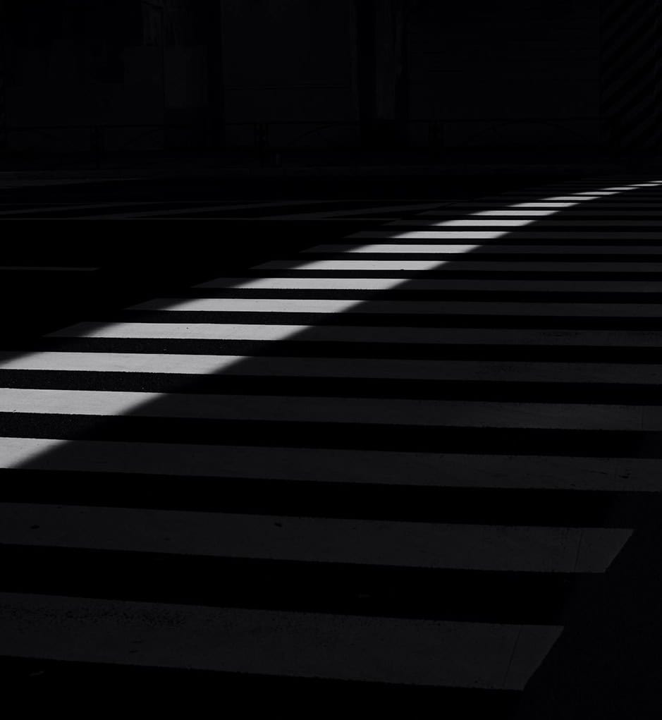 Shadows on Crosswalk Shadowed crosswalk with striped pattern in urban setting.